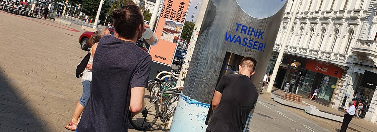 Zwei Männer stehen vor einem Trinkwasserspender